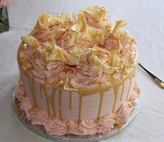 Pale pink icing drizzled with delicious caramel on top of shaved white chocolate. This delicious party cake is too beautiful to eat!